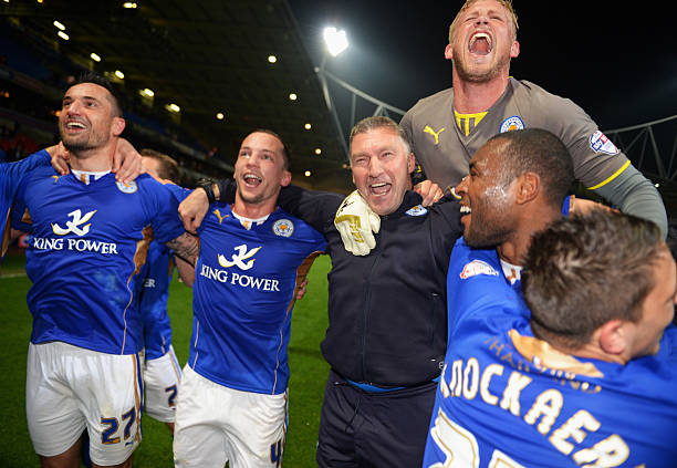 Goalkeeper Kasper Schmeichel of Leicester City jumps on the shoulders of Nigel Pearson, manager of Leicester City as he celebrates winning the Championship with team mates after the Sky Bet Championship match between Bolton Wanderers and Leicester City at Reebok Stadium 