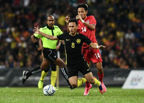 Malaysia's Nor Azam Abdul Azih (C) fights for the ball with Myanmar's Yan Naing Oo (R) during their men's football match
